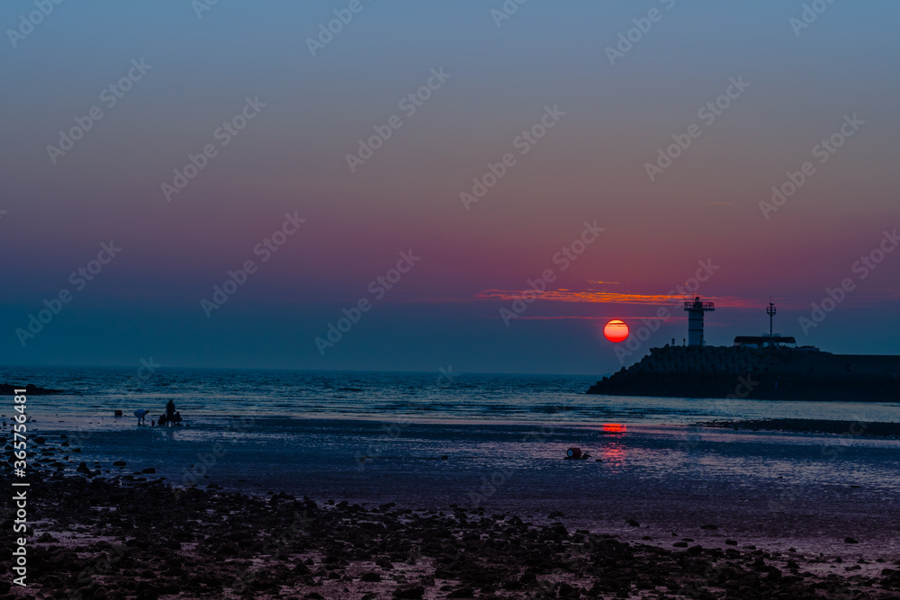Obraz premium Setting sun behind lighthouse