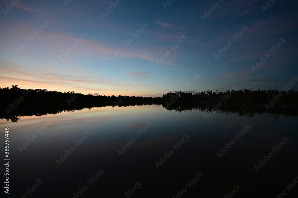 Brilliant colorful clouds in twilight reflected on calm water of Eco Pond in Everglades National Park, Florida on summer evening. Brilliant colorful clouds in twilight reflected on calm water of Eco Pond in Everglades National Park, Florida on summer evening.