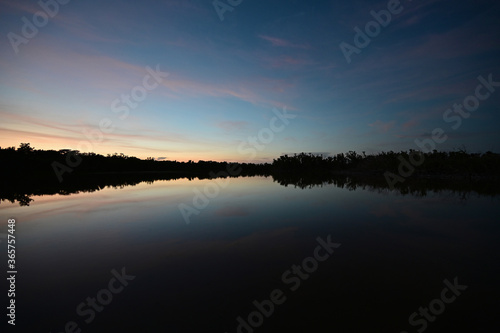 Brilliant colorful clouds in twilight reflected on calm water of Eco Pond in Everglades National Park  Florida on summer evening.