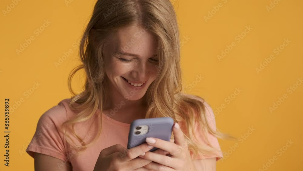 Beautiful blond girl flirting during messaging on smartphone over colorful background. Flirty expressions Beautiful blond girl flirting during messaging on smartphone over colorful background. Flirty expressions