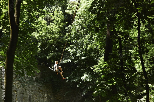 Young caucasian slackliner man doing slackline in the forest on a summer day.