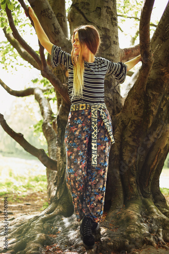 Young Caucasian woman in ethnic clothes climbing trees.