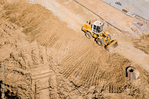 yellow wheel loader at construction site. heavy equipment is grading the land. top down aerial view