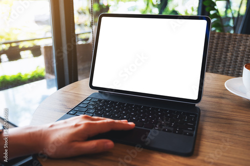 Mockup image of a woman touching on tablet touchpad with blank white desktop screen as a computer pc with coffee cup on the table