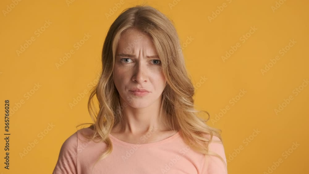 Young displeased blond woman angrily breathing on camera over colorful background. Irritated expression Young displeased blond woman angrily breathing on camera over colorful background. Irritated expression