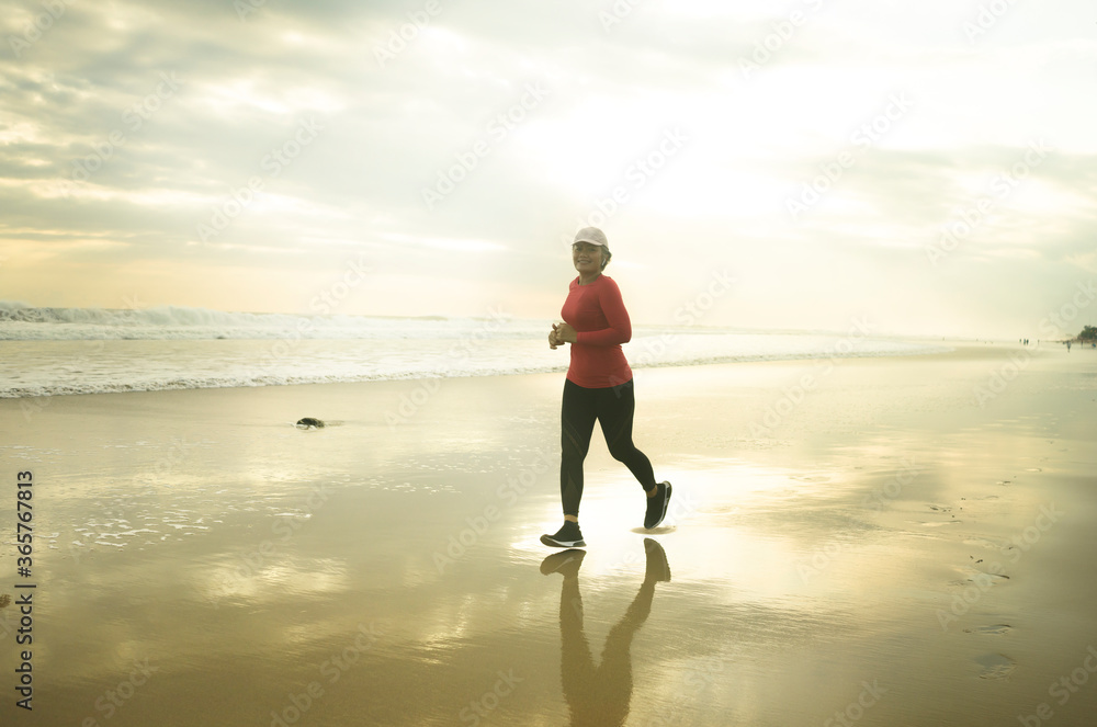 Silhouette of middle aged woman running on the beach - 40s or 50s attractive mature lady doing jogging workout enjoying fitness and healthy lifestyle at beautiful sea sunset Silhouette of middle aged woman running on the beach - 40s or 50s attractive mature lady doing jogging workout enjoying fitness and healthy lifestyle at beautiful sea sunset