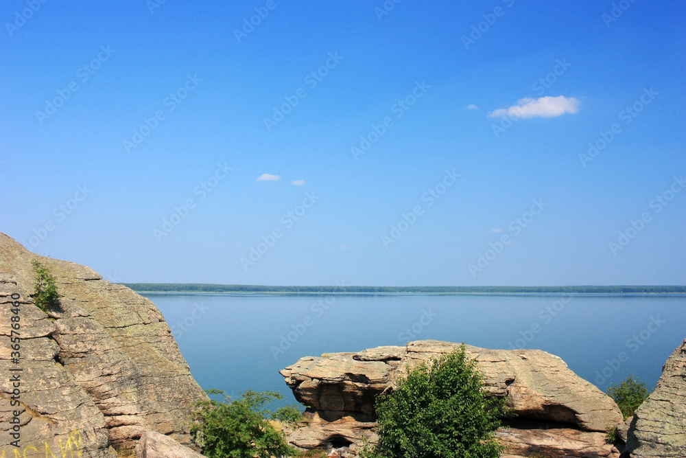 Stone granite rocks on the shore of a blue lake