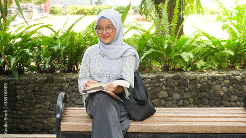 Asian hijab girl reading in the campus garden