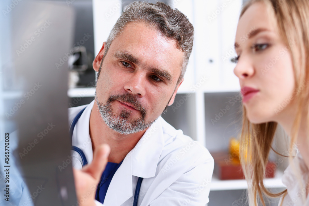 Obraz premium Mature male doctor hold in arm and look at xray photography discussing it with female patient portrait. Bone disease exam, medic assistance, cancer test, healthy lifestyle, hospital practice concept