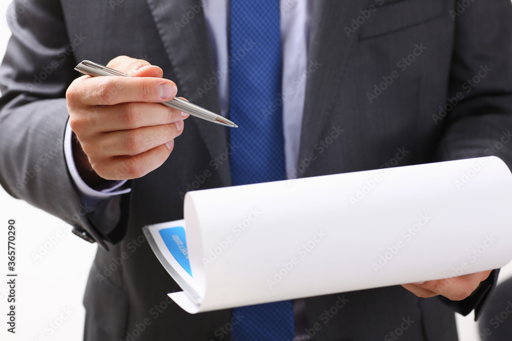 Hand of businessman in suit filling and signing with silver pen partnership agreement form clipped to pad closeup. Management training course, some important document, team leader ambition concept Hand of businessman in suit filling and signing with silver pen partnership agreement form clipped to pad closeup. Management training course, some important document, team leader ambition concept
