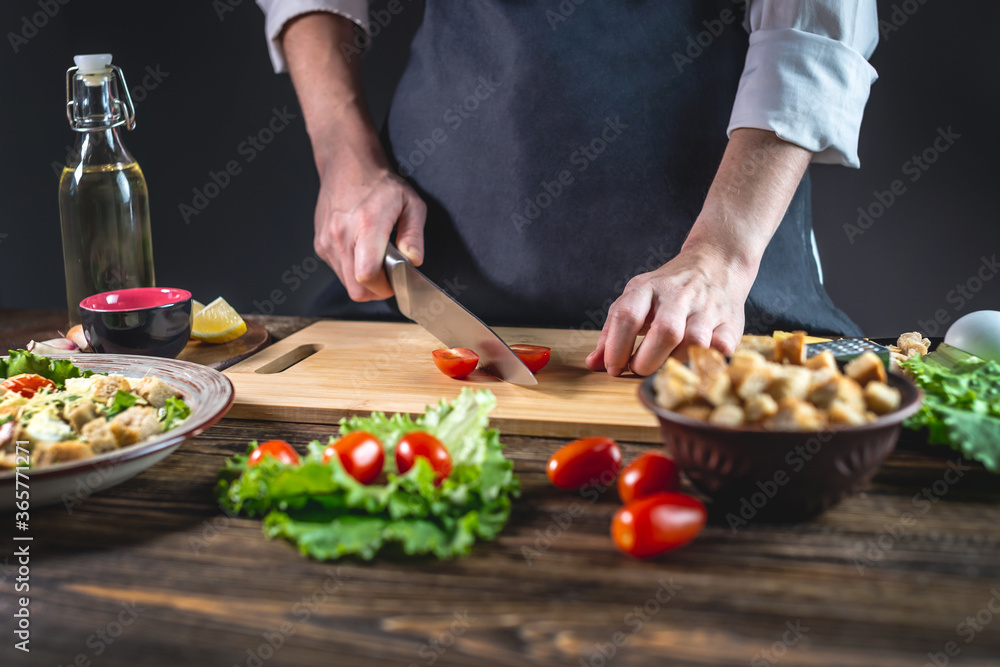 Chef is cutting the tomatoes. Concept of the process of preparing a fresh delicious salad