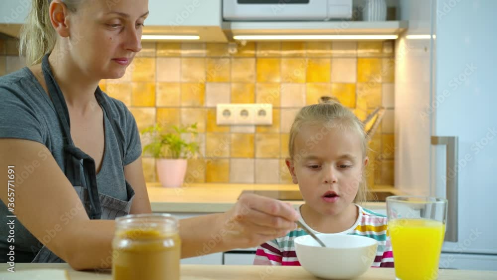 Mother helping to eat breakfast little daughter Mother helping to eat breakfast little daughter