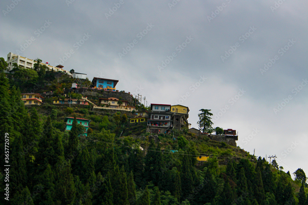 Landscape with colorful buildings built on the slop of mountain between the trees.