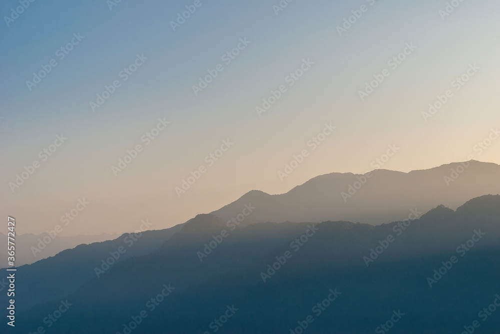 The dark silhouettes of the mountains covered by the fog at dawn.