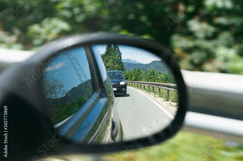 Car rearview mirror with reflection of the car following it, rear view  close up.