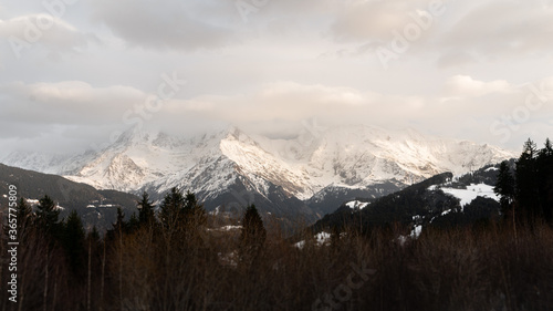 Big mountains in the french alps with forest on the foreground and snow during a colorful morning in winter