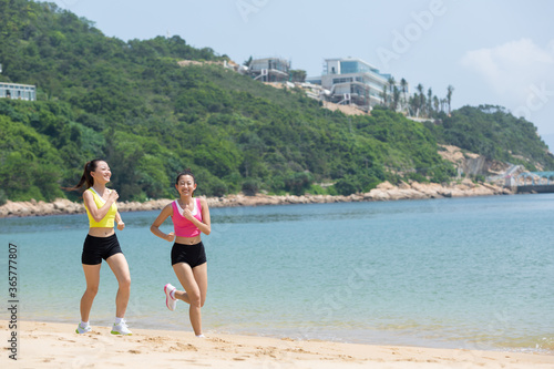 Two female friends running along the sea © JodieWang