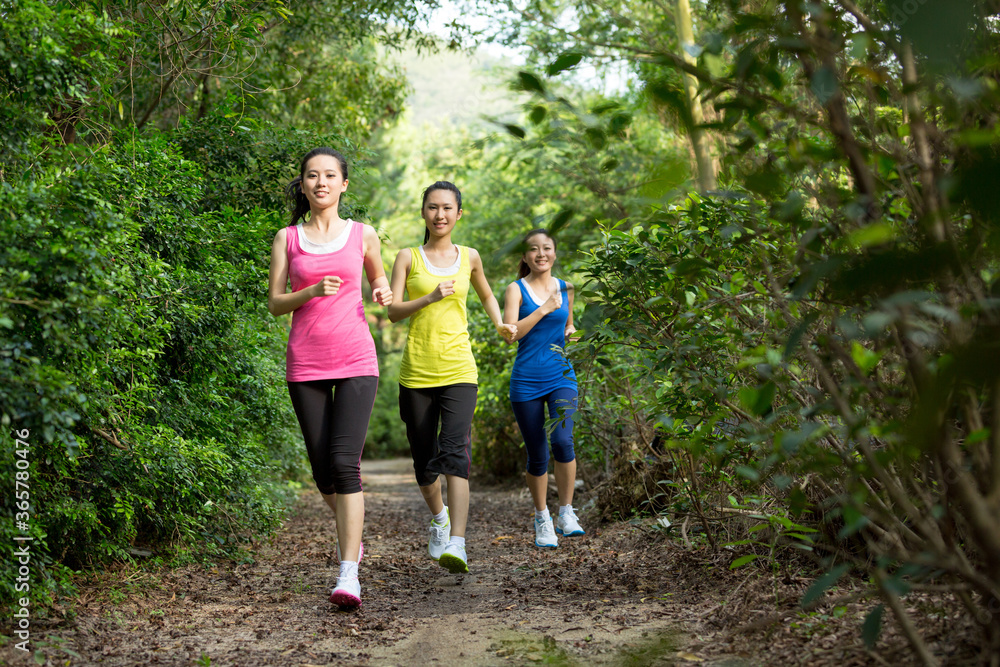 Obraz premium Three female friends running together on the path