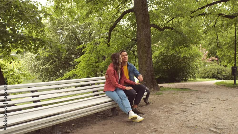 Young, happy, loving couple having date on the bench in the park. Relations, friendship and love. Young, happy, loving couple having date on the bench in the park. Relations, friendship and love.