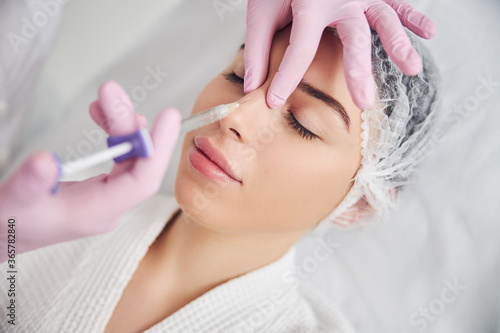 Calm female patient undergoing injectable beauty procedure photo