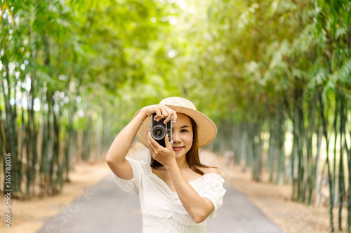 Young happy woman enjoying and taking a photo in the bamboo forest while traveling in summer © Kittiphan