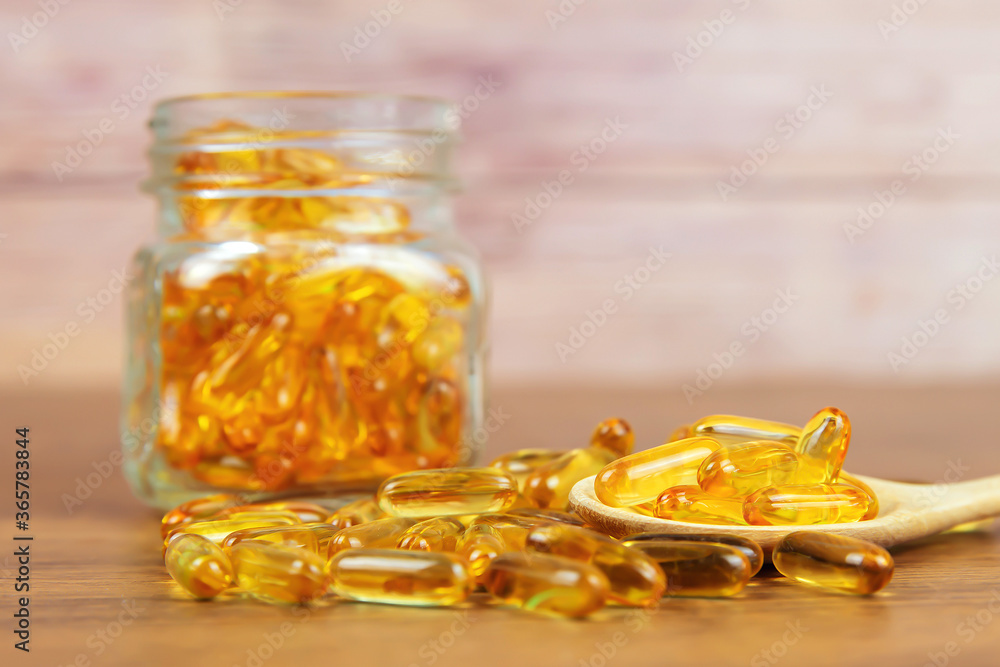 A pile of cod liver oil capsule in a wooden spoon. Dietary supplement for health-care concepts. A pile of cod liver oil capsule in a wooden spoon. Dietary supplement for health-care concepts.