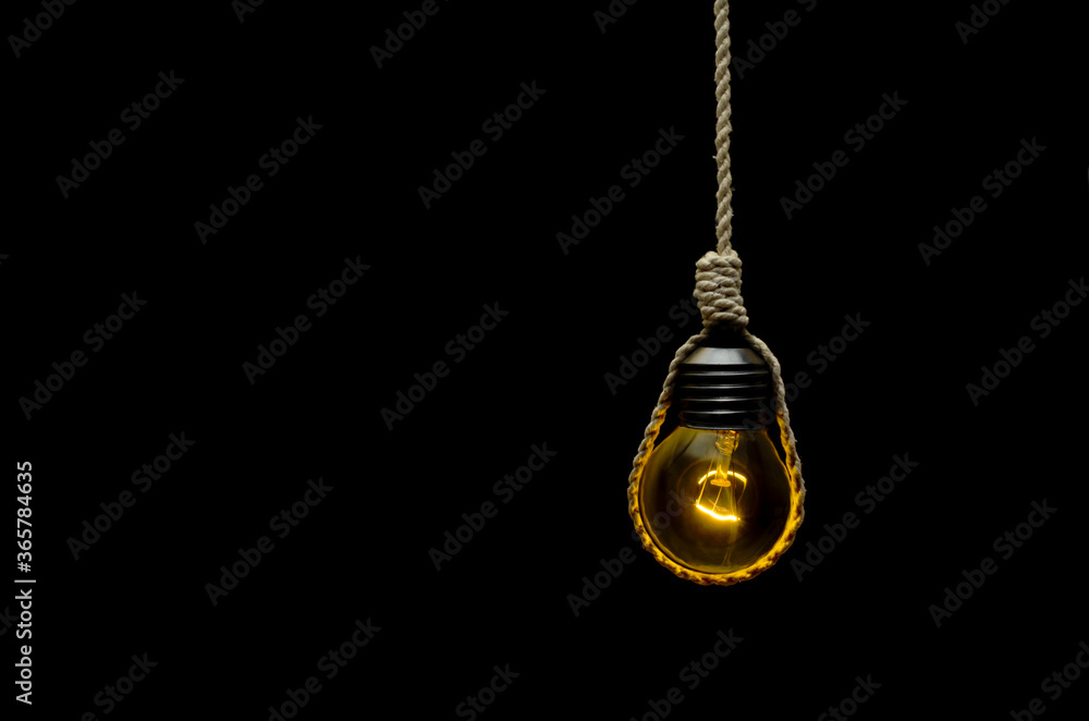 Bombilla encendida aislada sobre fondo megro colgada con una cuerda. Nudo de ahorcado Bombilla encendida aislada sobre fondo megro colgada con una cuerda. Nudo de ahorcado
