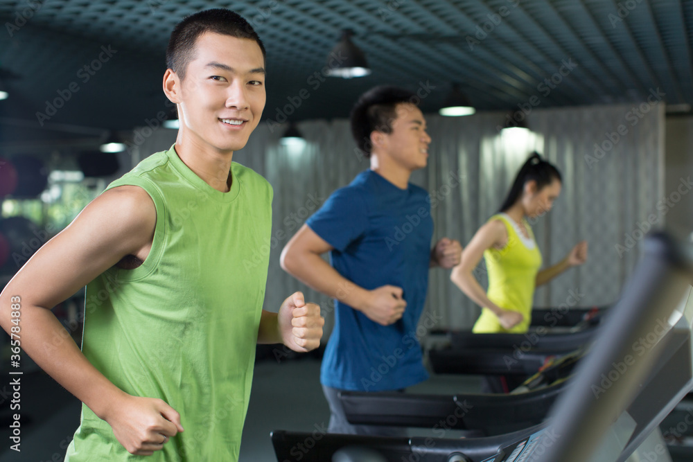 Young people running on treadmill in the gym Young people running on treadmill in the gym