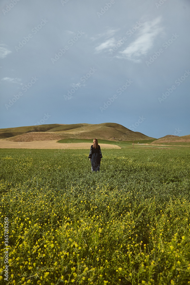 Young woman in traditional dress posing in a cultivated wheat field on a summer day