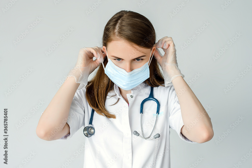 young surgeon doctor in latex protective gloves wearing medical mask on face. Man professional medic in medical gloves put on protective face mask. Personal protection. Coronavirus COVID-19 young surgeon doctor in latex protective gloves wearing medical mask on face. Man professional medic in medical gloves put on protective face mask. Personal protection. Coronavirus COVID-19