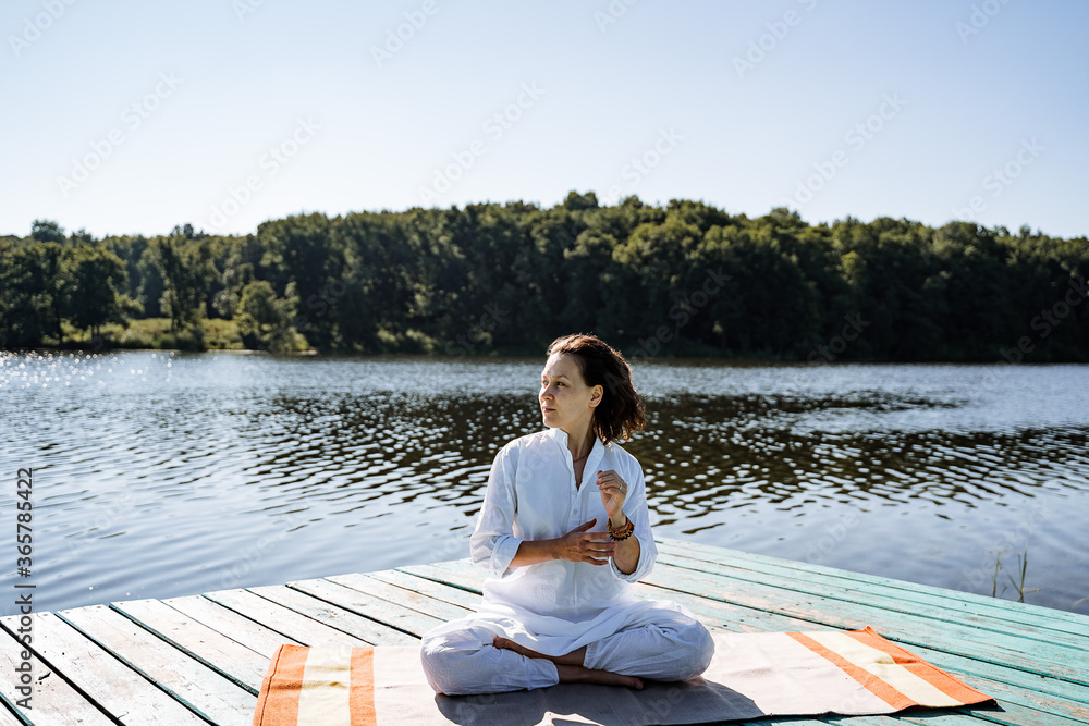 a young girl does yoga on a lake on a Sunny summer day, meditation, relaxing pose, solitude in nature, peace, relaxation, asana, healthy lifestyle, life style, Zen