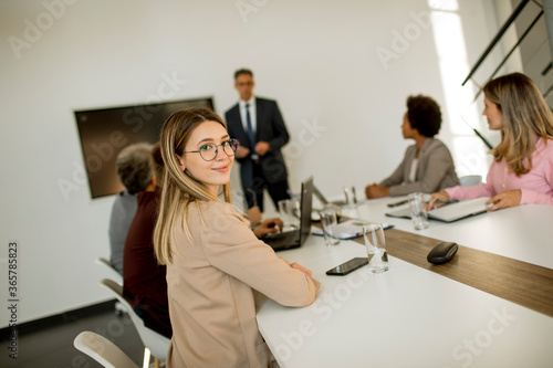 Young business woman sitting by the table with colleagues while working on new project