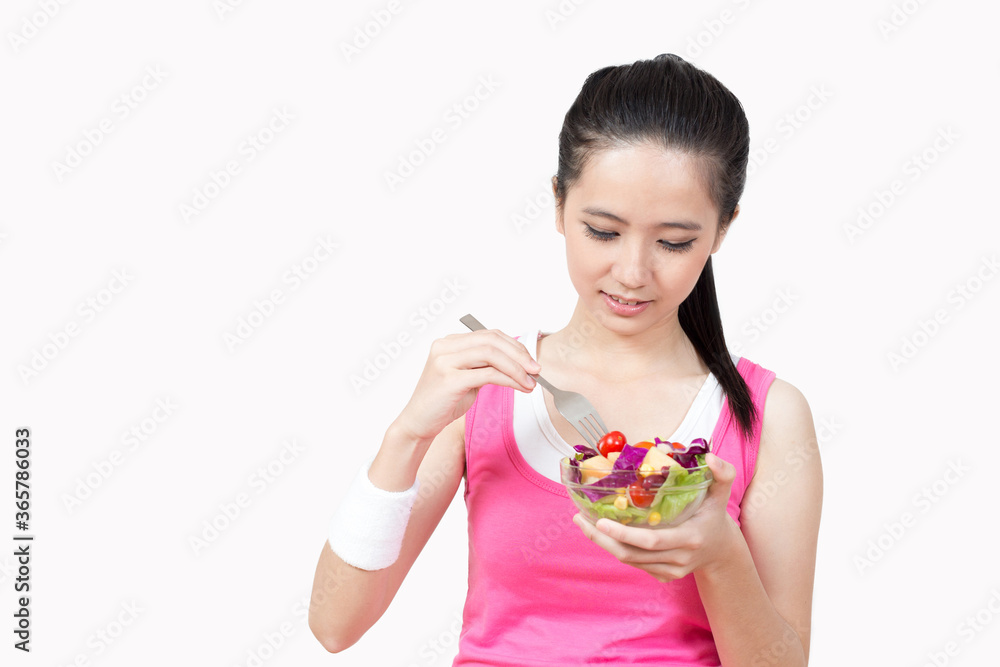 Young Asian woman eating salad after exercise in the gym Young Asian woman eating salad after exercise in the gym