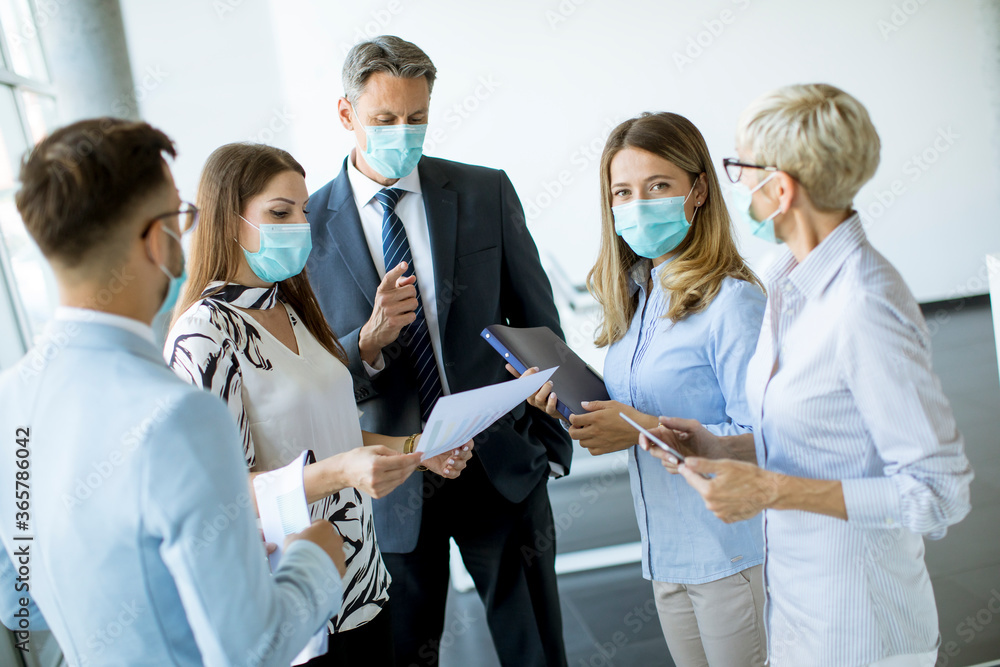 Business partners standing and looking at business results in office while wearing face masks sa an virus protection Business partners standing and looking at business results in office while wearing face masks sa an virus protection
