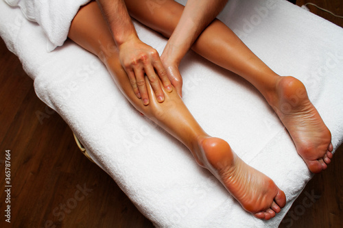Lymphatic drainage massage of legs and lower legs. Female feet in the hands of a masseur. photo
