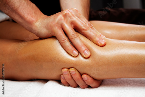 Lymphatic drainage massage of legs and lower legs. Female feet in the hands of a masseur.