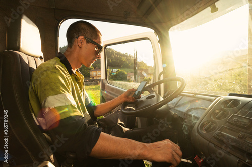 Young truck driver checking the smartphone at work © Dario