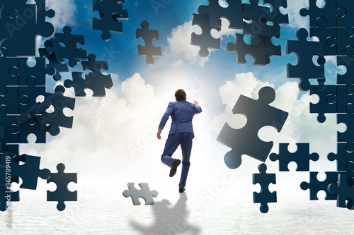 Businessman breaking the wall of jigsaw puzzle