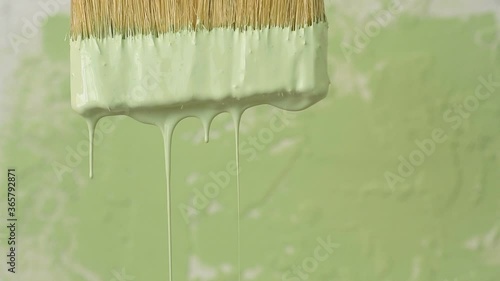 Thick green colour paint drop falls slowly freshly painted surface background. Slow motion artistic footage, paint pours from wide brush paper, plate, or table. Art house industrial decor concept
