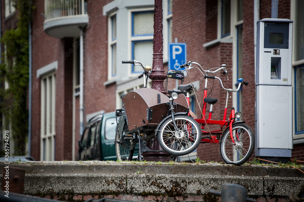 
red bicycle and bicycle with a basket for a child parked by a lamp on the streets of Amsterdam