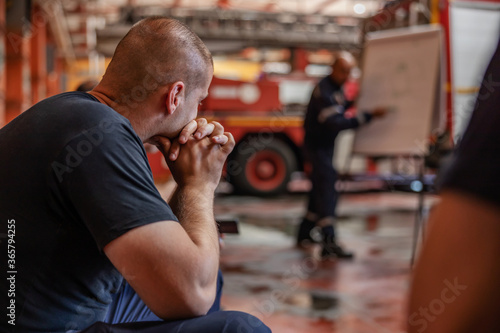 Closeup of firefighter sitting and listening boss who is talking about tactic how they gonna extinguish the fire. Fire brigade interior.
