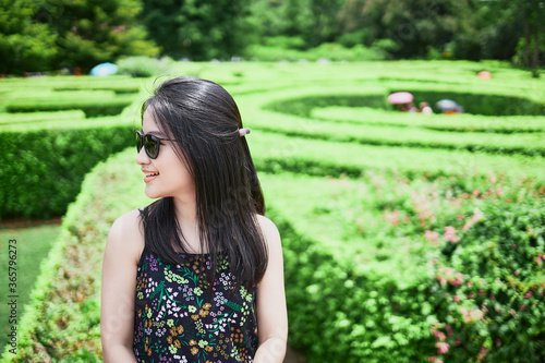 Asian girl looking in maze garden at noon