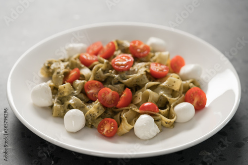fettuccine with pesto, tomatoes and mozzarella on white plate