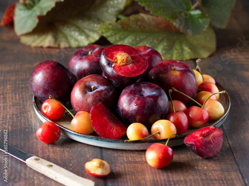 Fresh plums and sweet pink and yellow cherries on the plate, summer fruits