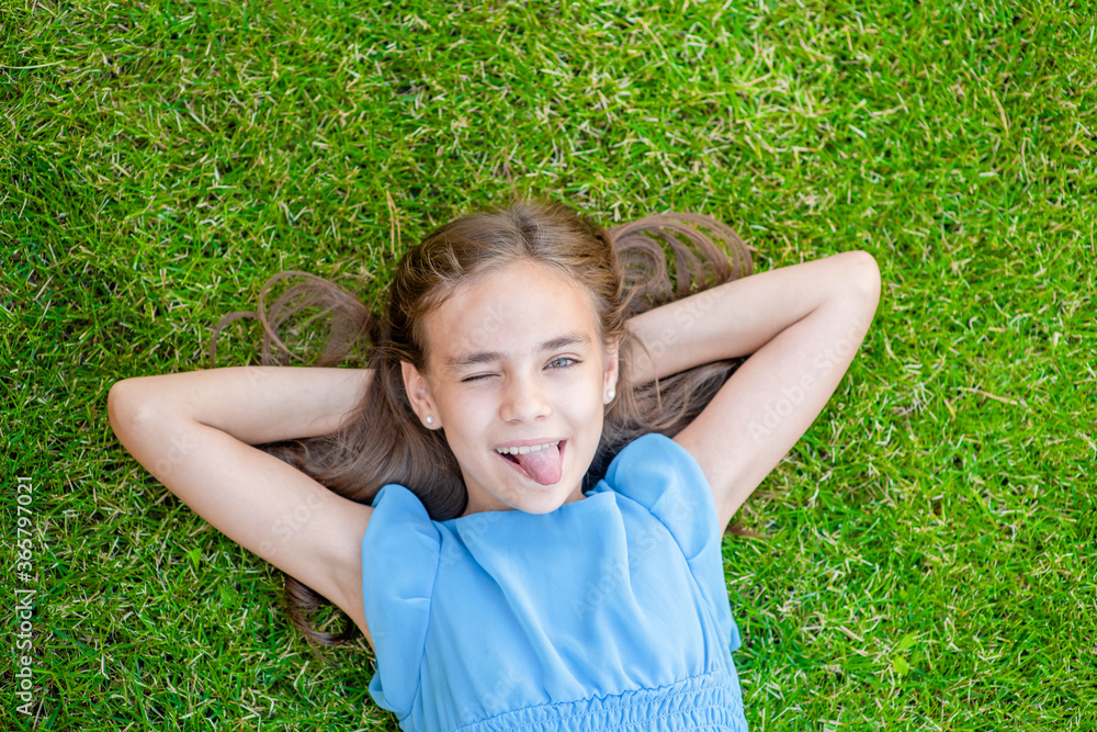 Joyful teen girl lying on grass, top down view Joyful teen girl lying on grass, top down view