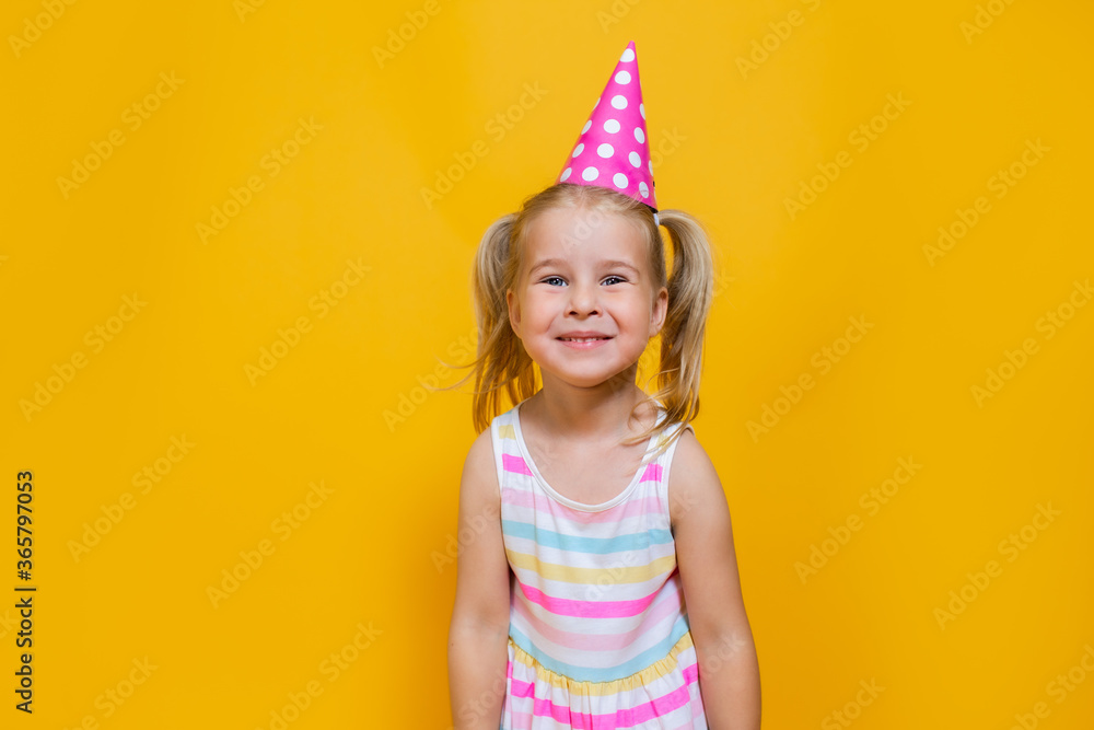 Happy birthday child girl with two ponytales in pink cap on colored yellow background. Happy birthday child girl with two ponytales in pink cap on colored yellow background.