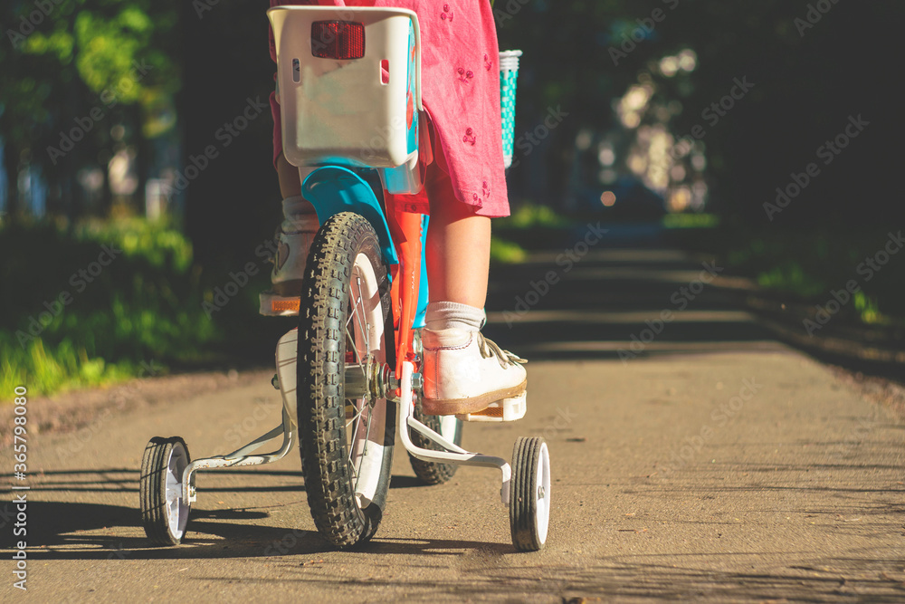 little girl in a red dress learns to ride a bike. children's bike with