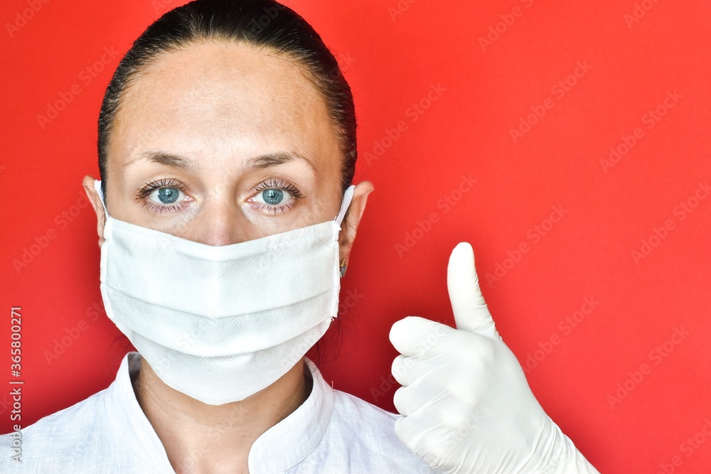 European young woman in protective mask and latex gloves showing thumb up on red background. space for text, close-up. healthcare concept, medicine. European young woman in protective mask and latex gloves showing thumb up on red background. space for text, close-up. healthcare concept, medicine.
