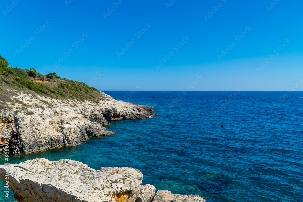 Beautiful rocky Cliffs with people on boats in Kamenjak National Park, Istria, Croatia