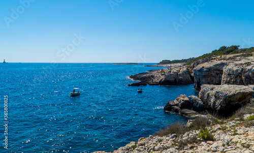 People on boats near rocky cliffs in Kamenjak, Istria, Croatia